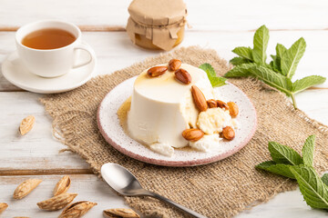 Ricotta cheese with honey and almonds on white wooden. side view, close up.