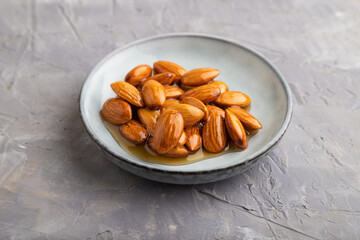 Almonds with honey on gray concrete. side view, close up.