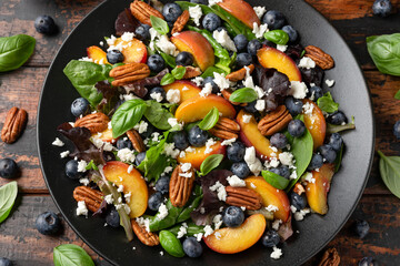 Peach, blueberry salad with vegetables, feta cheese and pecan nuts. Healthy summer food