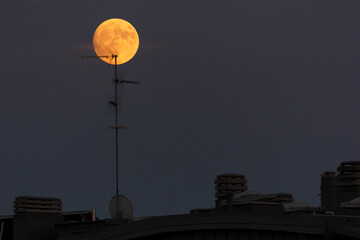 Full blood red moon in a city sky, tv antennas are visible in the foreground. Image shot at 300mm.