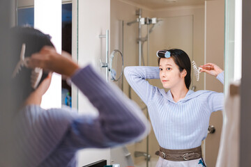 鏡の前で髪のセットをする若い女性