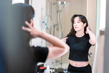 Fototapeta na wymiar 鏡の前で髪のセットをする若い女性