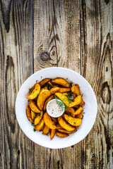 Tasty baked potatoes with dill and mayonnaise on wooden table 