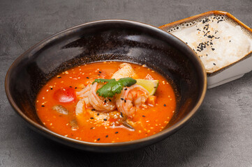 tom yam with seafood in a dark dish and rice