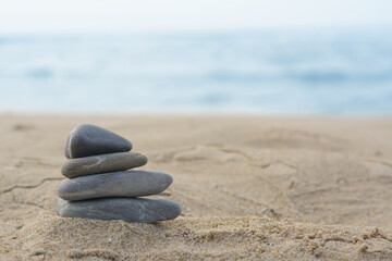 Fototapeta na wymiar Stack of stones on sandy beach near sea, space for text