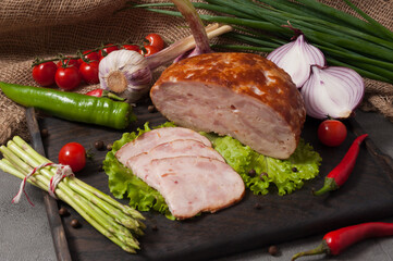 boiled and smoked chicken roll on a wooden board decorated with fresh vegetables