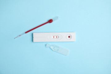 Disposable express hepatitis test kit on light blue background, flat lay