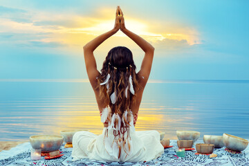 Yoga Meditation at Sunset Beach. Peaceful Woman relaxing with Tibetan Singing Bowls. Indian Women...