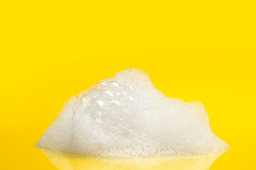 Drop of fluffy bath foam on yellow background - obrazy, fototapety, plakaty