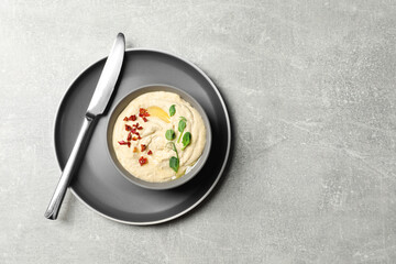 Tasty hummus with garnish in bowl served on grey table, top view. Space for text
