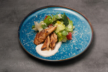 caesar salad with chicken fillet on a blue plate