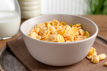 Tasty cornflakes with milk in bowl on table, closeup