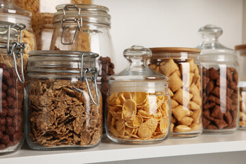 Glass containers with different breakfast cereals on shelf