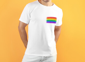 Young man wearing white t-shirt with image of LGBT pride flag on orange background