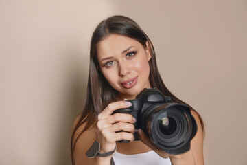Fototapeta premium Professional photographer with camera on beige background