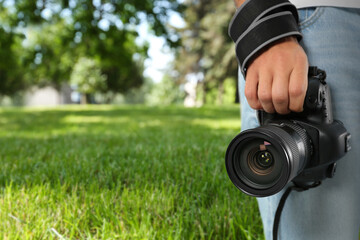 Fototapeta premium Professional photographer with modern camera and blurred view of park, space for text