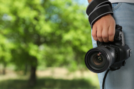 Professional photographer with modern camera and blurred view of park, space for text