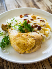 Boiled chicken thigh with white rice and lemon creamy sauce with raisins on wooden table