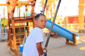 The girl rides on a swing in the playground. Children's outdoor carousels