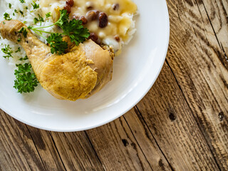 Boiled chicken thigh with white rice and lemon creamy sauce with raisins on wooden table