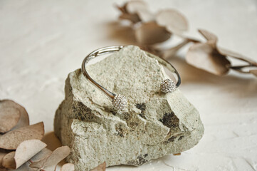 Diamond gold bracelet on stone with eucalyptus leaves, white background