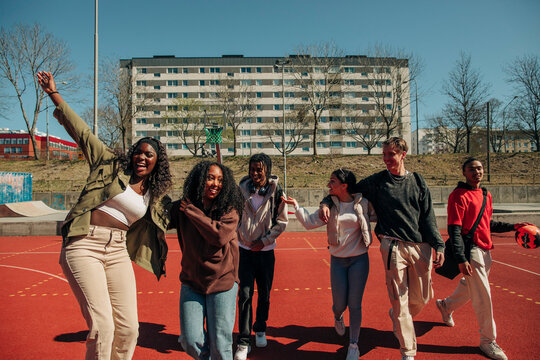 Cheerful multiracial friends enjoying at sports court on sunny day - Powered by Adobe