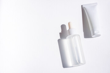 Cosmetic bottles with shadow on white wall background