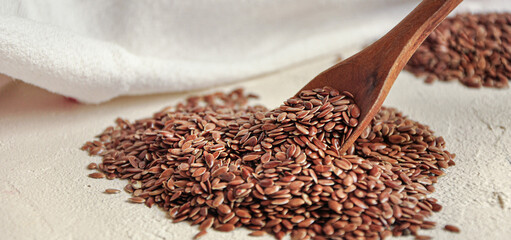 Flax seeds in wooden spoon on white background