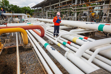 Male worker inspection at steel long pipes and pipe elbow in station oil factory during refinery...