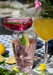 Mango, strawberry cocktails and rose lemonade on a garden table. Summer cocktails close up photo. Refreshing drinks in different glasses. 
