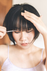 Fototapeta premium Young adult authentic asian woman self cutting bangs haircut with scissors