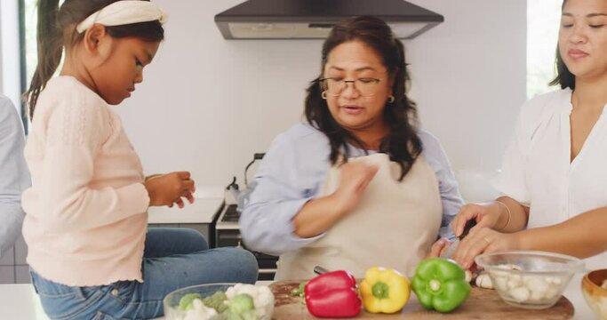 Family cooking in the kitchen together. Siblings helping their mother prepare a wholesome nutritious recipe meal in their modern home. Parent teaching her daughter how to cook healthy vegetable foods