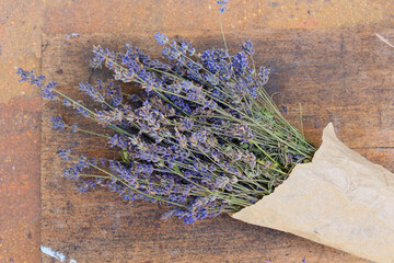 Bouquet of lavender in paper packaging. Lavender flower bouquet on old rustic wooden background....