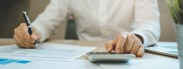 Close up hand of professional accountant review tax paperwork and signing signature on the table in workplace