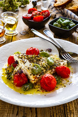Roasted tomatoes with feta cheese and broad bean served  on wooden table