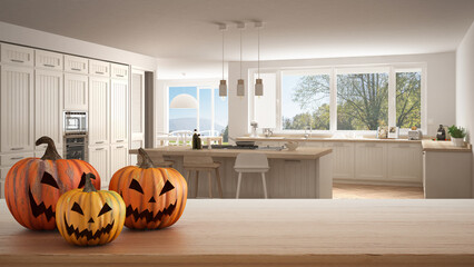 Halloween carved pumpkins on wooden table. Autumn decoration over interior design scene. Classic wooden kitchen with island and stools