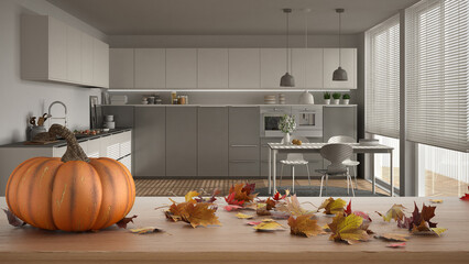 Autumn pumpkins still life on wooden table. Thanksgiving Halloween decoration over interior design scene. Modern gray kitchen with dining table and big window