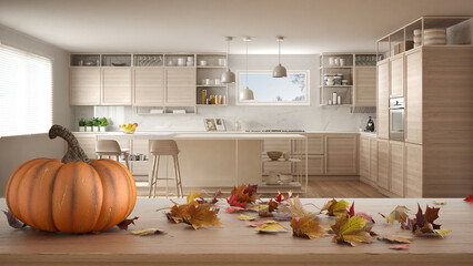 Autumn pumpkins still life on wooden table. Thanksgiving Halloween decoration over interior design scene. Modern minimalist kitchen with island and cabinets with shelves