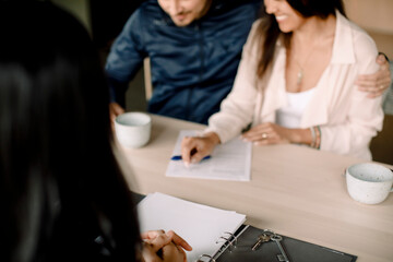 Real estate agent with couple signing contract at table in new house