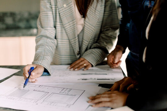 Midsection of real estate agent showing blueprint to customers