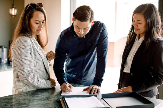 Customer with real estate agent signing contract in kitchen of new house