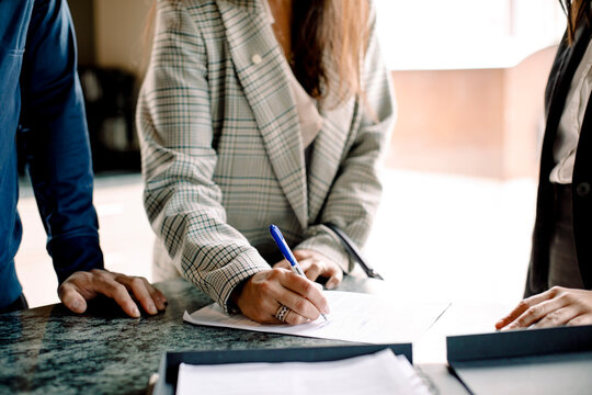 Midsection of couple signing contract with real estate agent in kitchen
