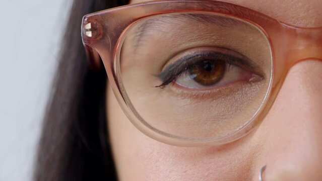 Woman watching or gazing with trendy optometry vision glasses. Closeup of eyes looking forward while wearing optician prescription eyewear. Detail of lady with eyeliner makeup and mascara cosmetics