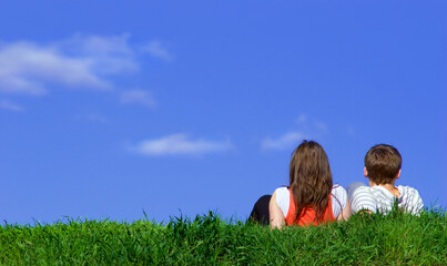 Back view of Romantic Couple in love sitting on grass field and watch the clear blue sky. Couple love dating in holiday trip concept.