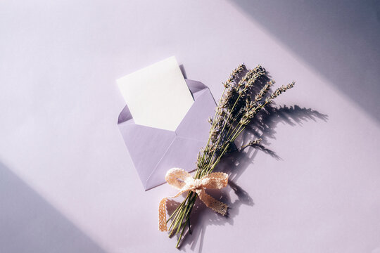 Envelope With A Blank Sheet And A Bouquet Of Lavender On A Lilac Background In Sunlight. Top View, Flat Lay, Mockup