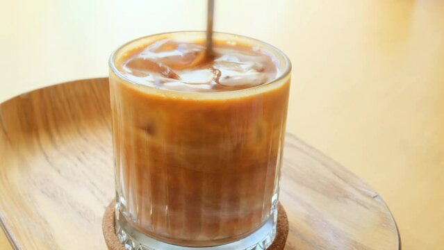 Iced coffee stir in glass on a table in a cafe, closeup.