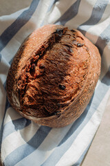 loaf of rye bread with cranberry on the stripes towel in shadows