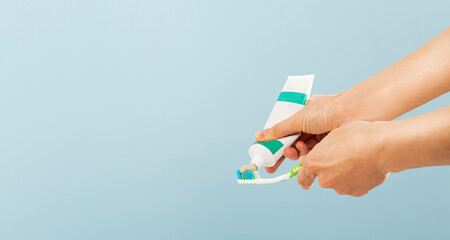 Woman squeezing toothpaste on brush against color background