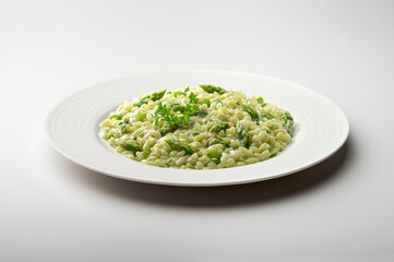 Risotto with green asparagus and parsley in white plate