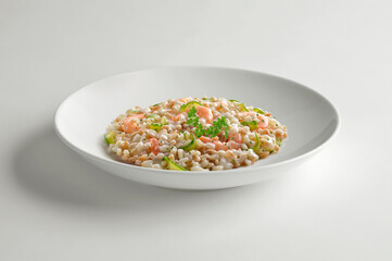 White bowl of spelled barley rice risotto with shrimp and zucchini and parsley